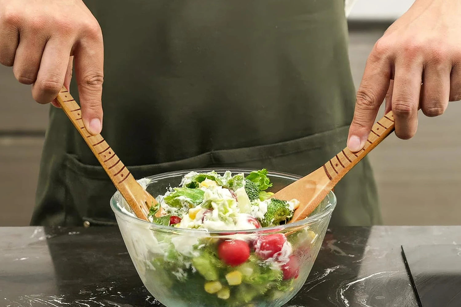Two bamboo serving utensils with fret markings and inlay dots down each handle, being used to toss a salad